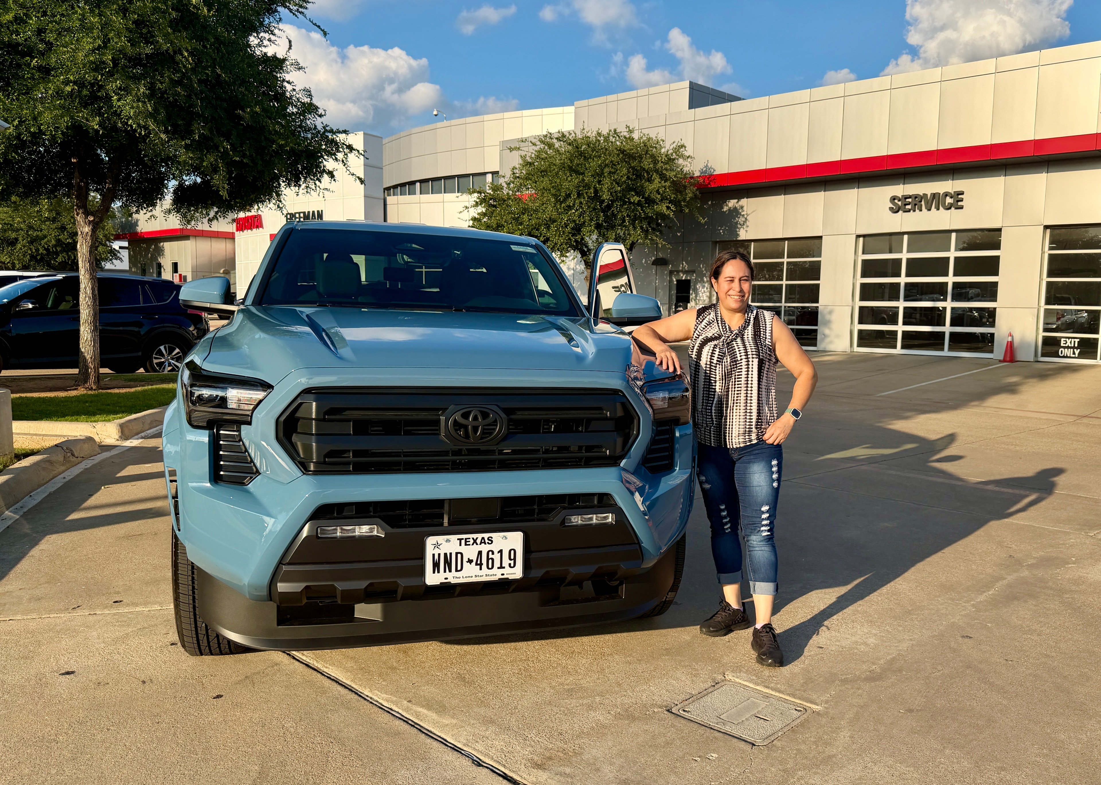 Happy customer with her new blue Toyota Tacoma at Freeman Toyota DFW
