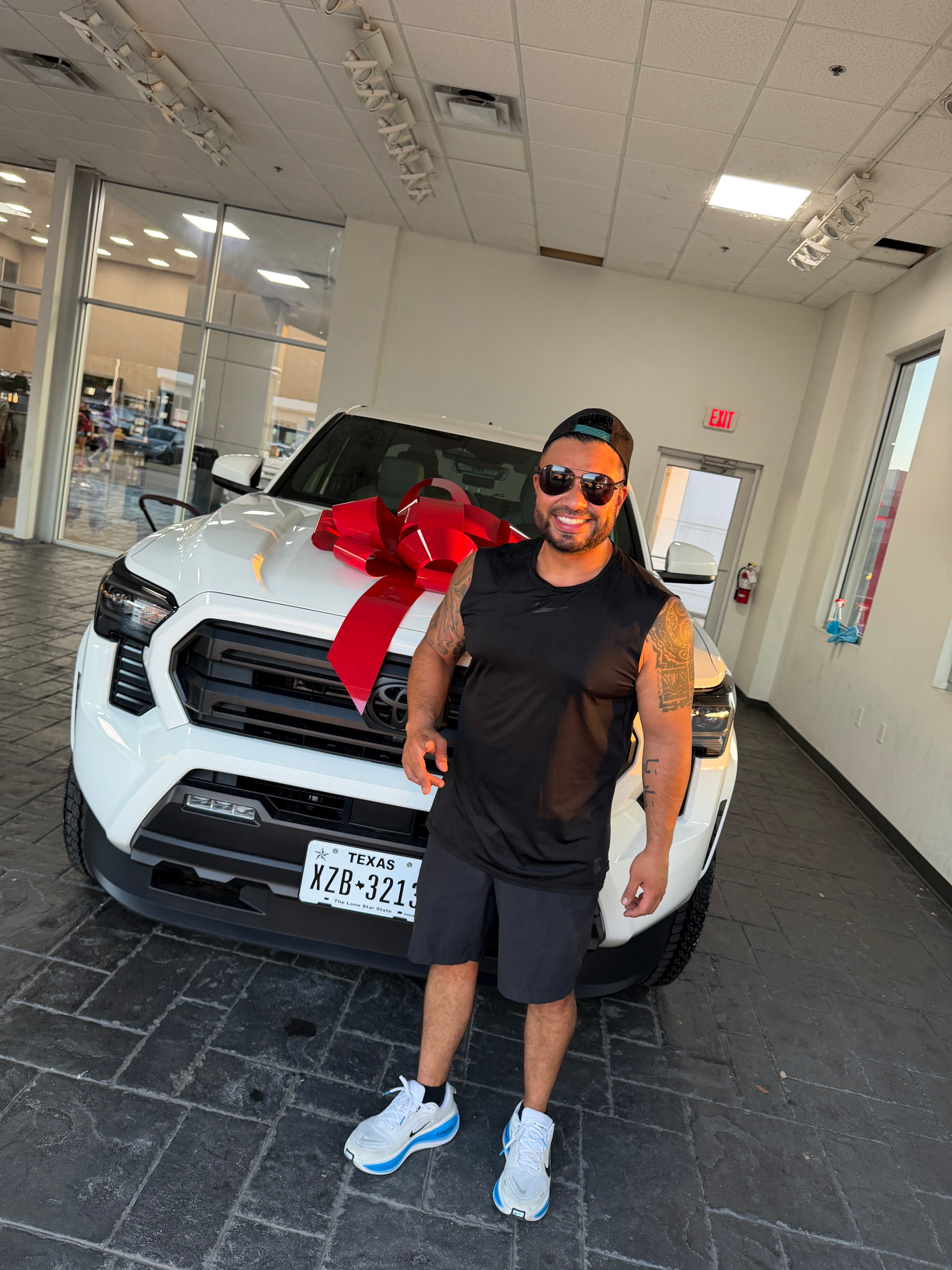 Excited customer with his new white Toyota and red bow at Freeman Toyota Hurst TX