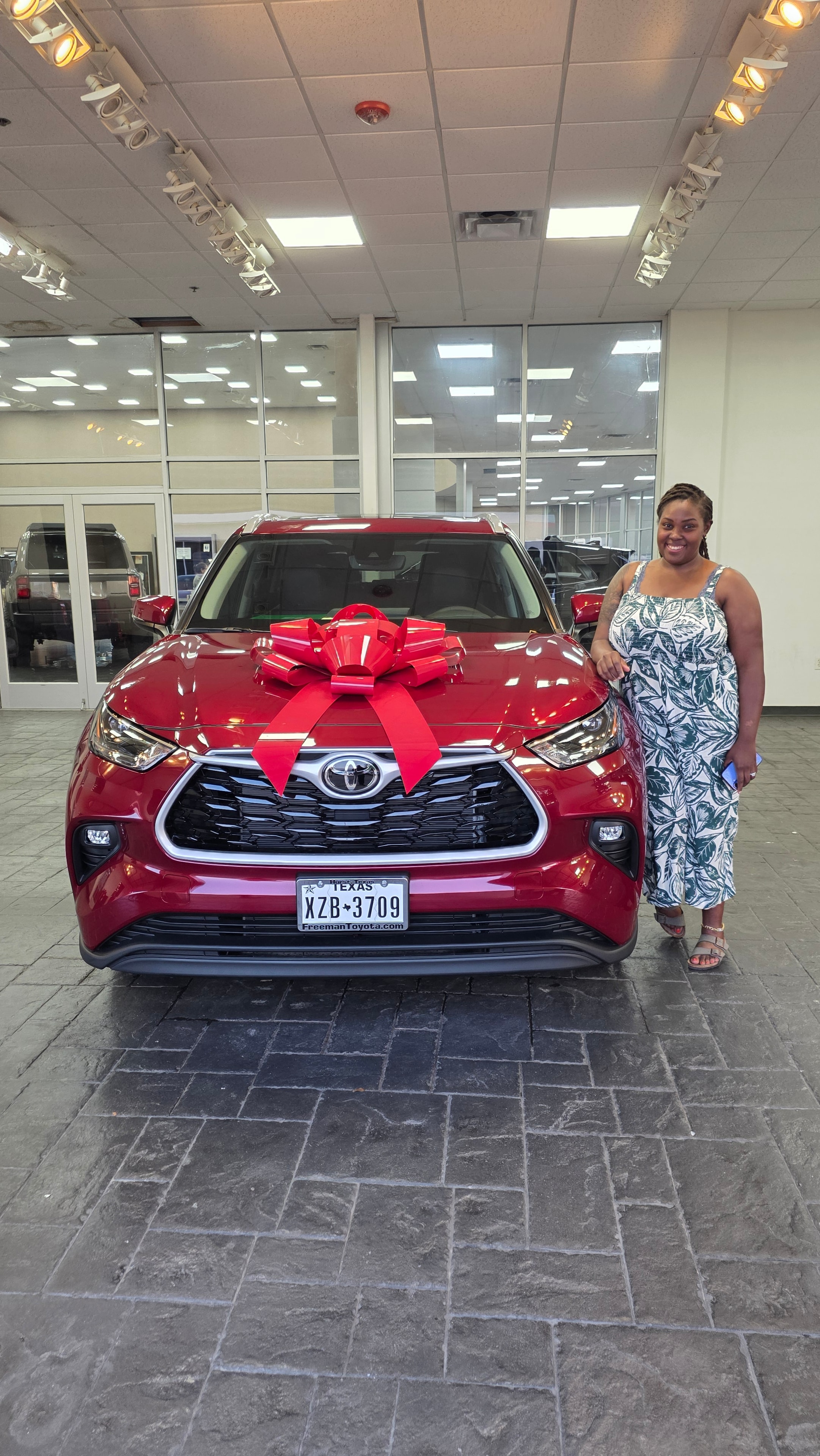 Happy customer with new red Toyota and red bow at Freeman Toyota dealership Hurst TX